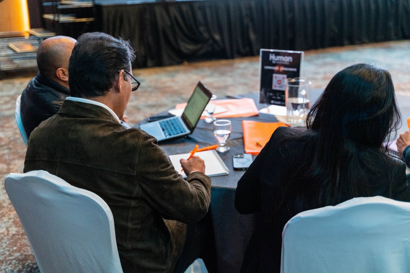 Participantes trabajando en una mesa con portátil y cuaderno